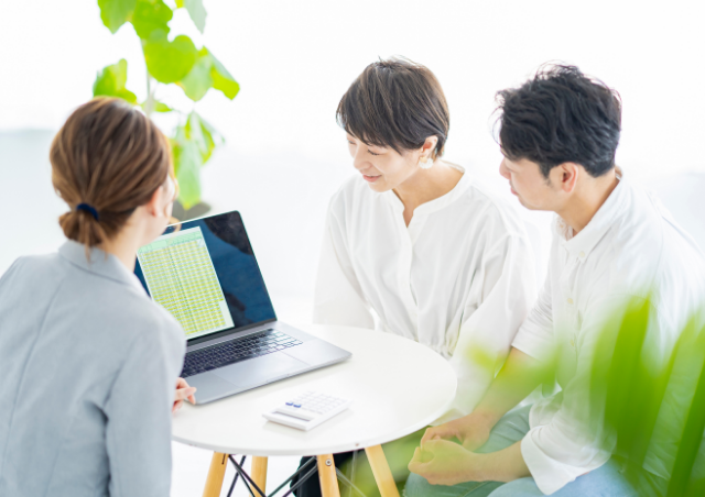 住宅購入を検討する夫婦と説明する不動産の女性